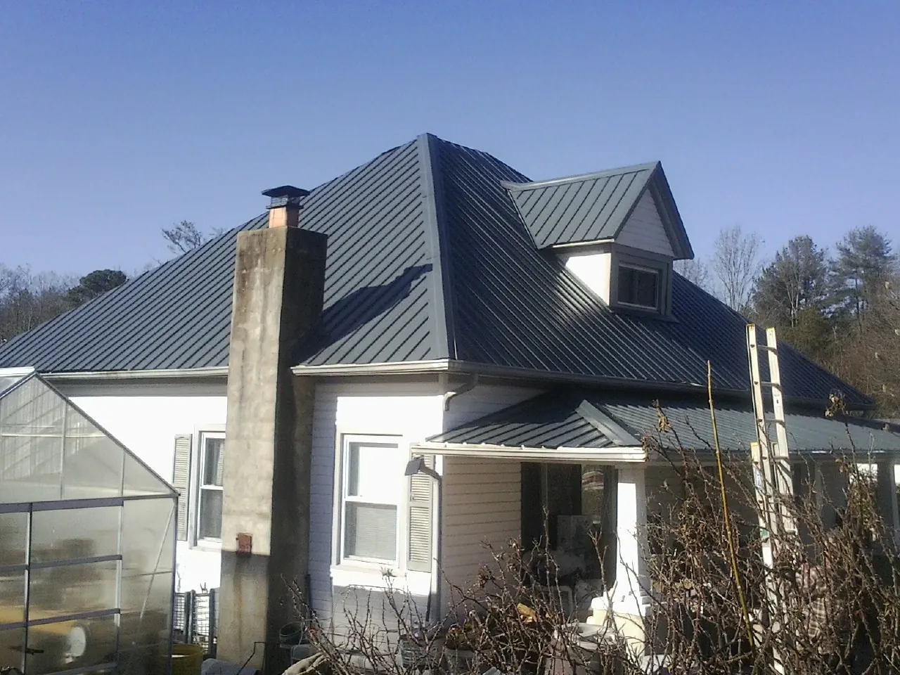 Dark blue standing seam metal roof on a white farmhouse with dormer — Slate & Tile Roof Repair by Roofing Brothers in Wawarsing