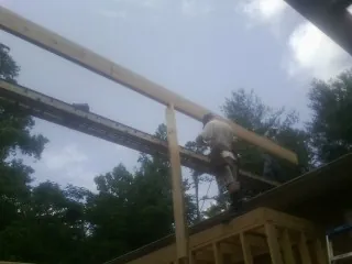 Carpenter setting a ridge beam over a new addition frame — Ice Dam Removal by Roofing Brothers in Wawarsing