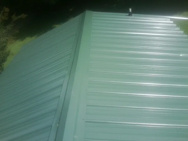 New green metal panels meeting at the ridge of a roof — Flat Roof Repair work by our crew in Wawarsing