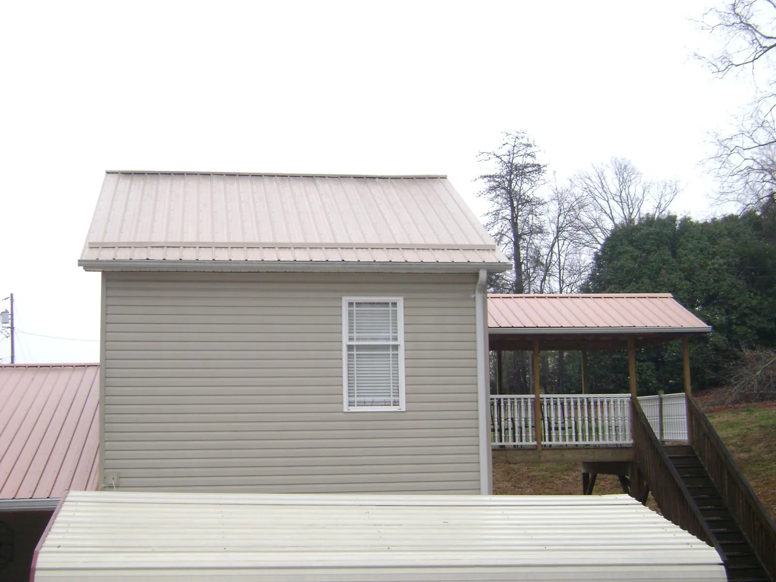Tan metal roofs on a two story addition and attached porch, from a Roof Replacement job in Wawarsing