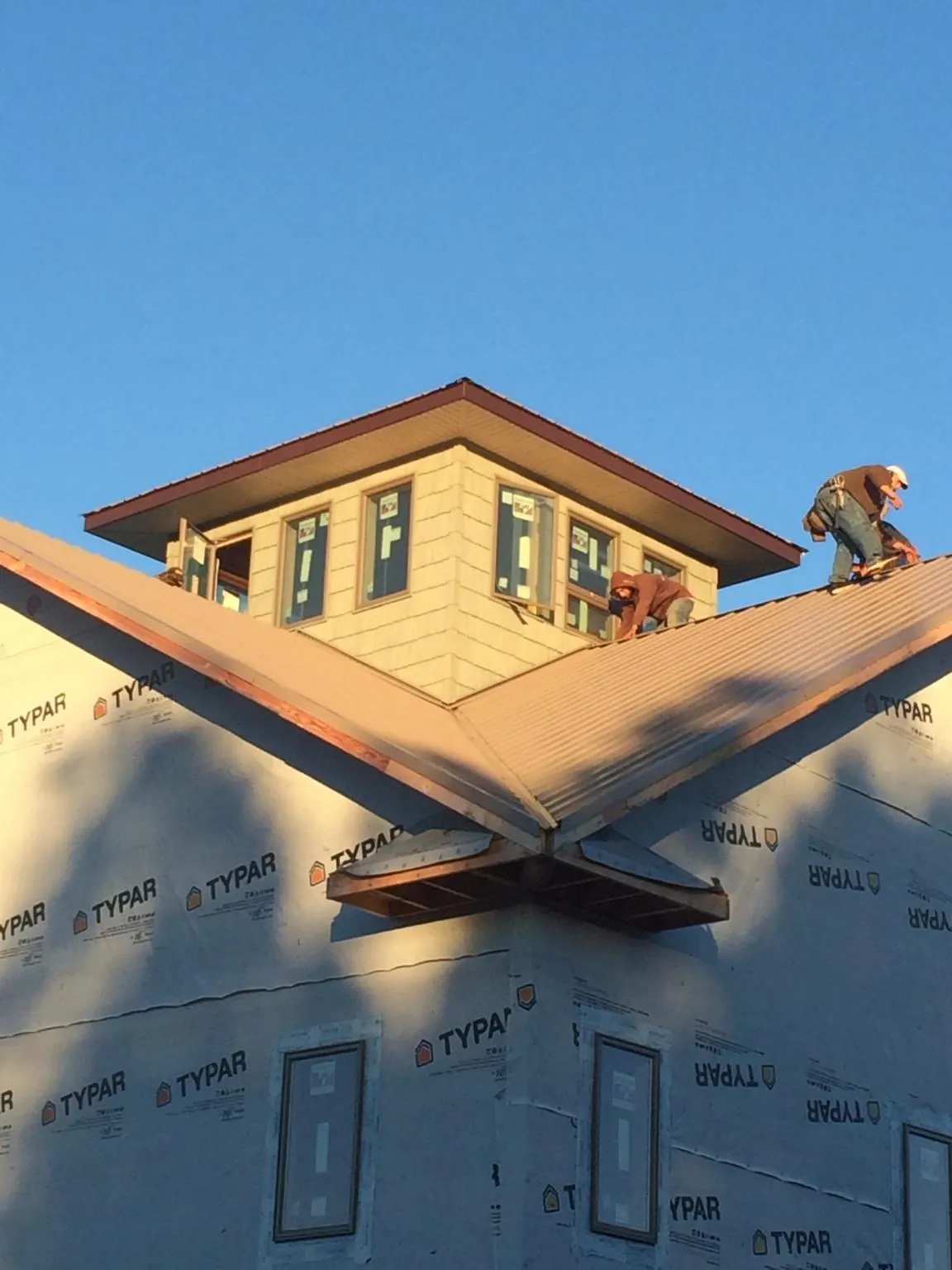 Roofers working around a rooftop cupola on a new metal roof at sunset — Roof Waterproofing in Wawarsing by Roofing Brothers